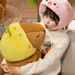 Woman in a pig hat holding a capybara plush in a pineapple hood