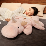 Woman sleeping on a bed hugging a pink and white dragon plush body pillow.