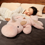 Woman sleeping on a bed hugging a pink and white dragon plush body pillow.