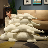 Woman next to stacked white and mint green dragon plush body pillows of different sizes on the floor.