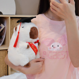 Woman hugging a white graduation capybara plush with a red tassel and Graduate sash