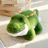 Close-up of a green alligator plush lying down with a friendly smile