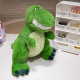 Green T-Rex dinosaur plush with a wide smile on a table next to a white organizer, showing its pale green belly.