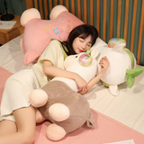 Woman sleeping on a bed hugging a gray alpaca plush with a leaf sprout