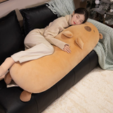 Woman sleeping on a sofa with a long tan capybara bolster pillow