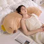 Woman lying on a bed with long tan capybara body pillows