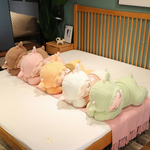 Five sleeping sheep plush pillows in sweaters lined up on a white bed