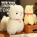 Large white and small yellow alpaca plushies with red bell collars on a wicker stool