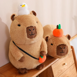 Capybara plush with a white duck on its head and another with an orange on a wooden shelf