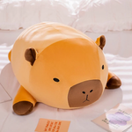 Chubby orange capybara plush pillow with a brown muzzle lying on a white bed