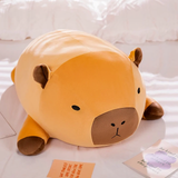 Chubby orange capybara plush pillow with a brown muzzle lying on a white bed