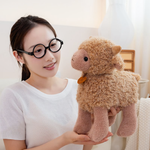 Woman with round glasses holding a brown curly lamb plush