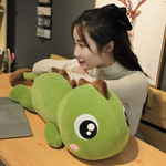Woman leaning on a green dinosaur plush pillow with brown spikes on a wooden table.
