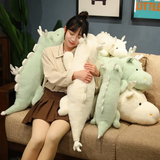 Woman hugging a white and mint green dragon plush pillow on a sofa.