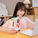 Woman at a desk with a laptop and a white graduation capybara plush