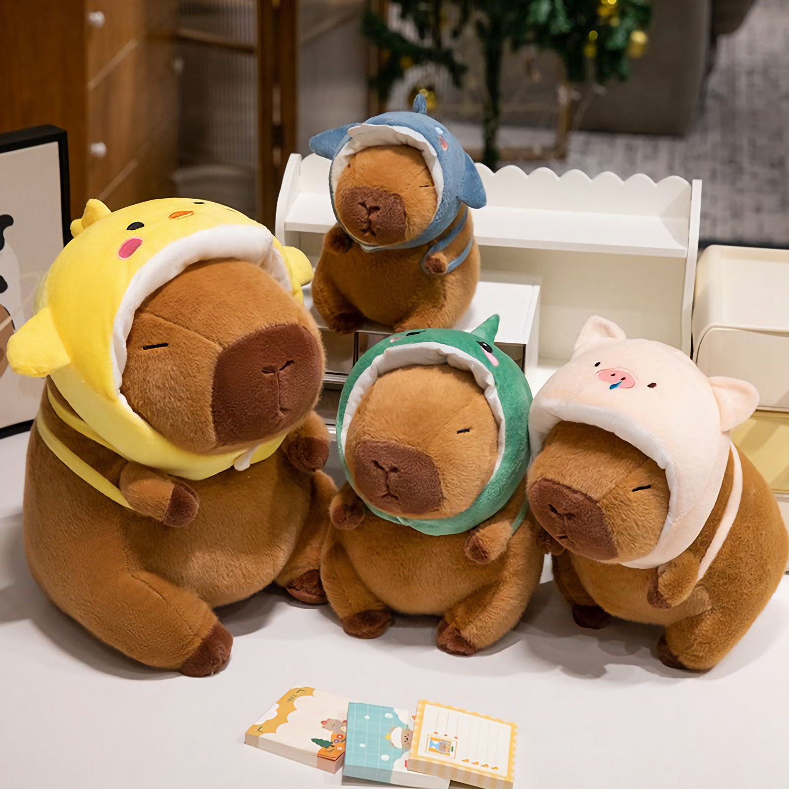 Capybara plushies in chick, shark, dinosaur and pig hoods on a shelf