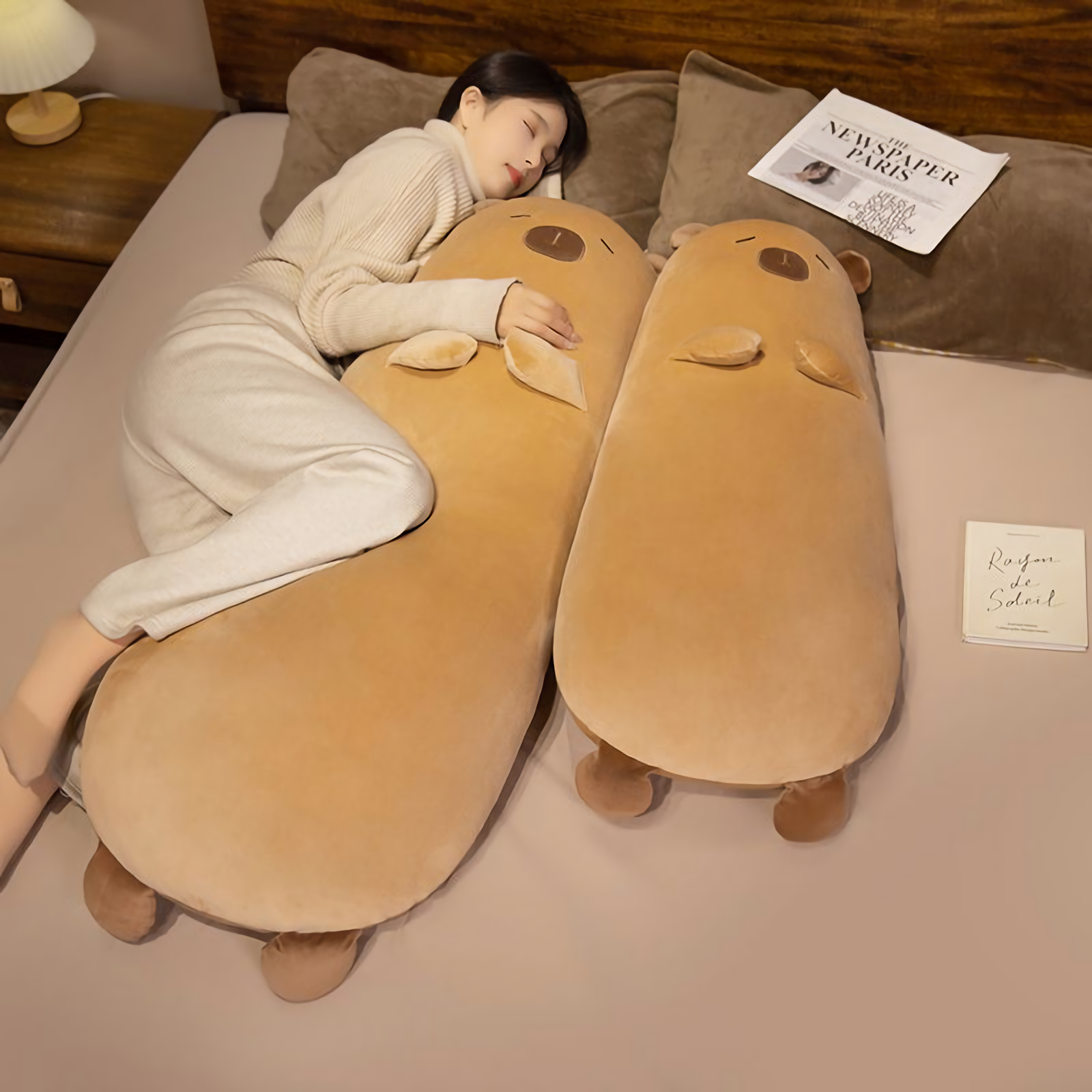 Woman sleeping on a bed with two tan capybara bolster pillows