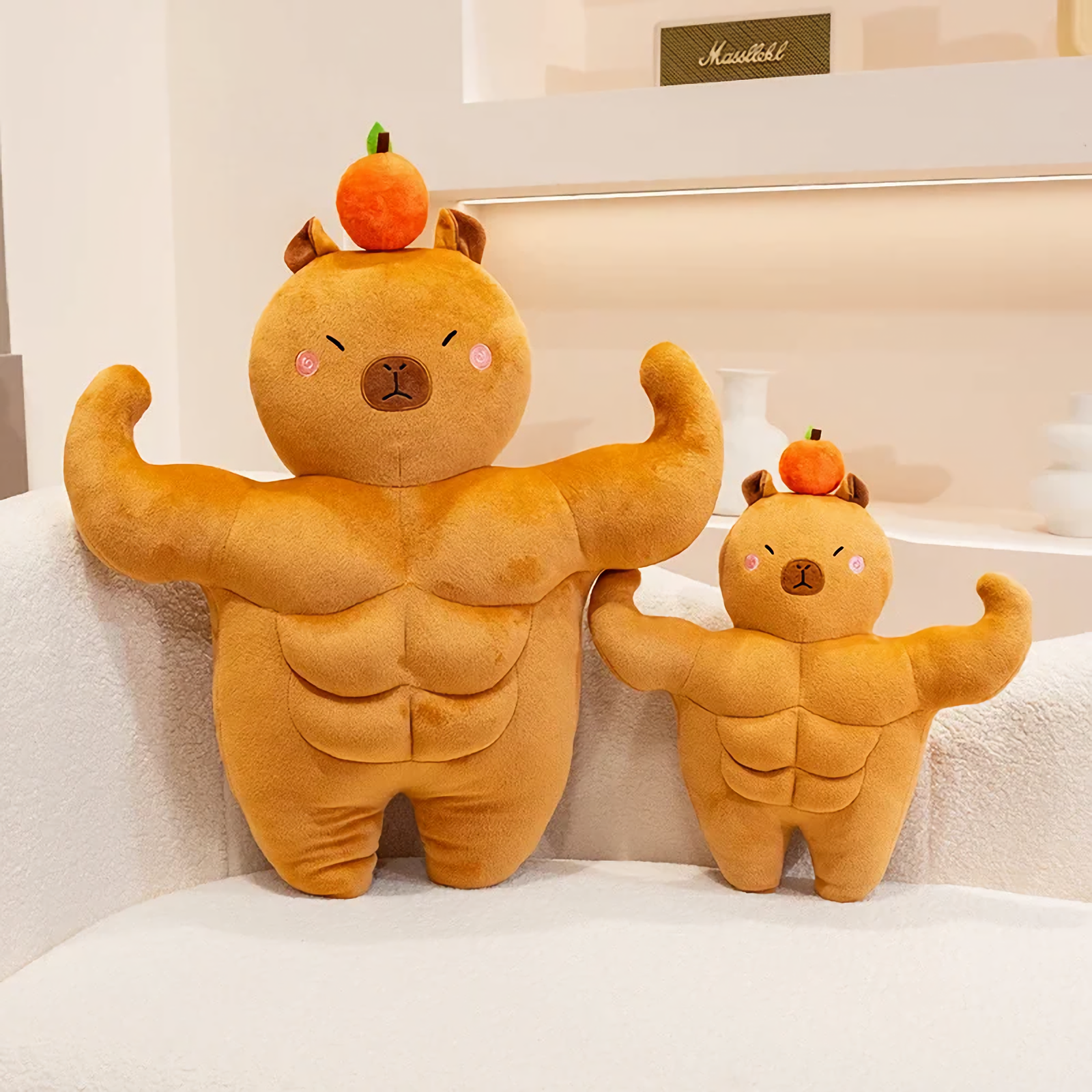 Small and large muscle capybara plushies with oranges on their heads on a sofa