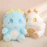 Two Kawaii fluffy baby dragon plush toys, one blue and one white, sit side by side on a light fabric surface.