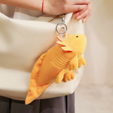Yellow axolotl plush with a clip ring hanging from a white tote bag held by a woman