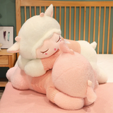 White sleeping sheep plush pillow resting on a pink one on a bed