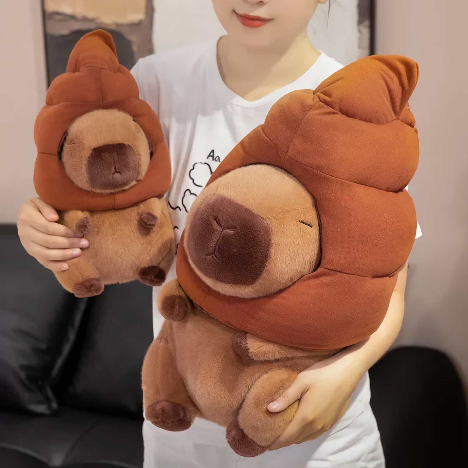 Person holding two capybara plushies with brown swirl hats