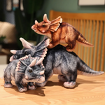 Gray and brown Triceratops plushes on a wooden table, gray ones in a trio, brown one perched on top.