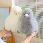 Hands holding a white alpaca plush and a gray alpaca plush facing each other
