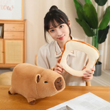Woman holding a bread slice frame beside a capybara plush