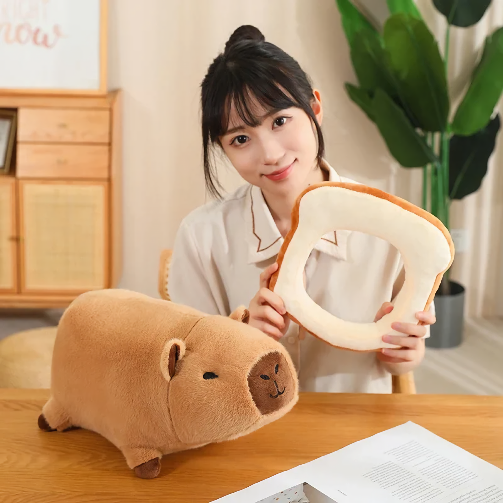 Woman holding a bread slice frame beside a capybara plush