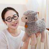 Woman with round glasses holding a gray curly lamb plush