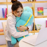Woman smiling while hugging a long blue dinosaur plush with a yellow back ridge