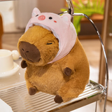 Capybara plush in a pink pig hood on a metal shelf