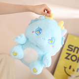 A woman's hand holding a blue fluffy baby dragon plush, showing sparkly star eyes and golden horns.