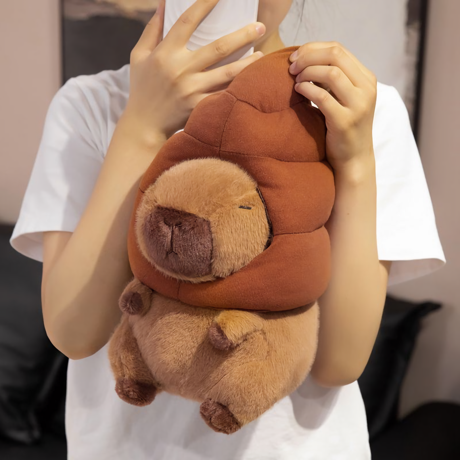 Woman holding a capybara plush with a brown swirl hat