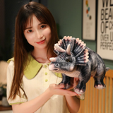 Woman holding gray Triceratops plush with detailed frill and horns, smiling indoors.