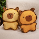 Two bread capybara plushies side by side on a white sofa