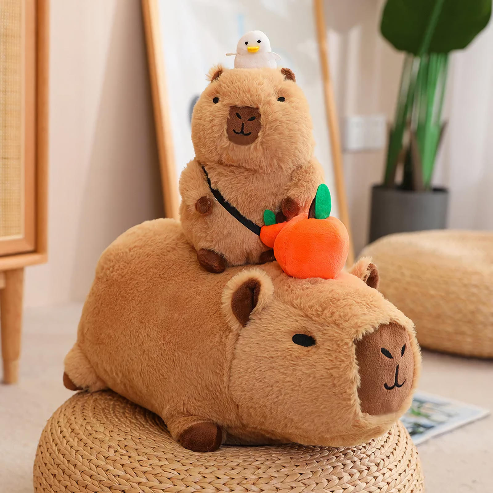 Small capybara plush with a duck sitting on a lying capybara with an orange