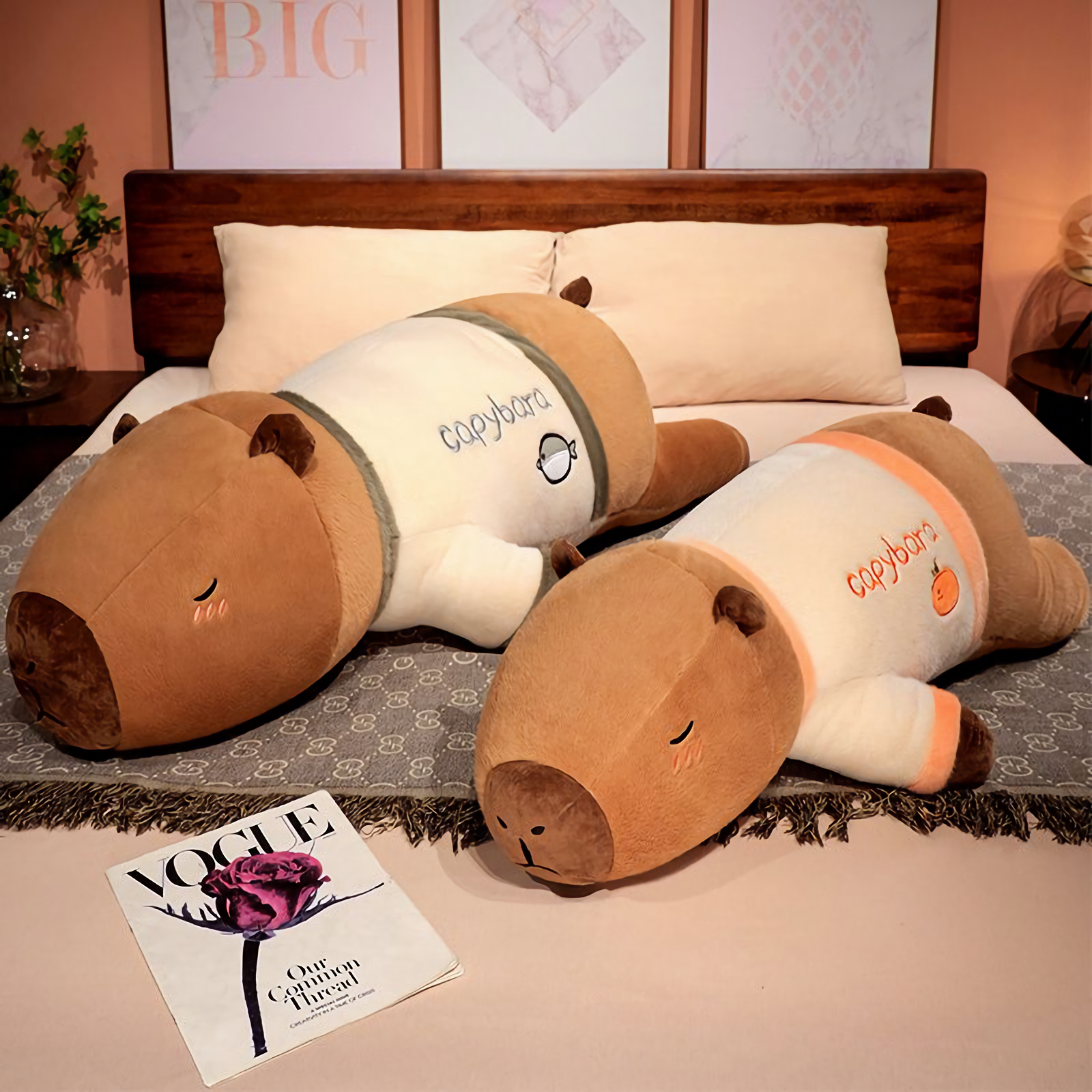 Two lying capybara plush pillows in cream shirts on a bed