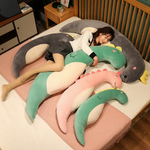 Woman lying on a bed surrounded by curved green, gray and pink plush body pillows