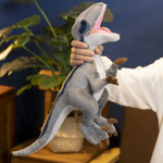 A woman holds a gray Velociraptor plush, 40cm, with an open mouth in front of indoor plants.