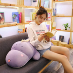 Woman sitting on a sofa reading with a purple dinosaur plush pillow on her lap