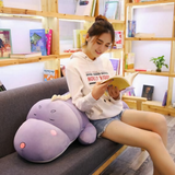Woman sitting on a sofa reading with a purple dinosaur plush pillow on her lap