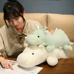 Woman with mint green and white dragon plushes on a table.
