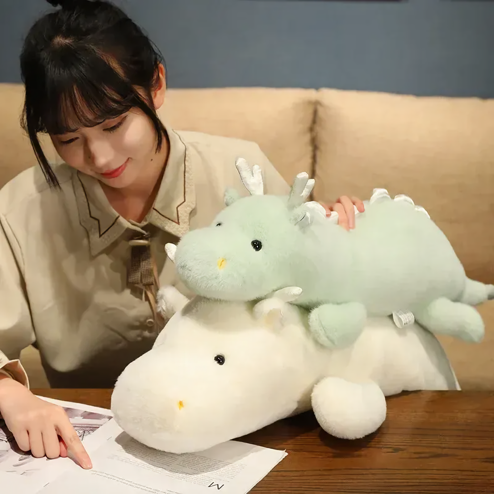Woman with mint green and white dragon plushes on a table.