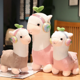 Gray, pink and small pink alpaca plushies with headphones sitting on a bed