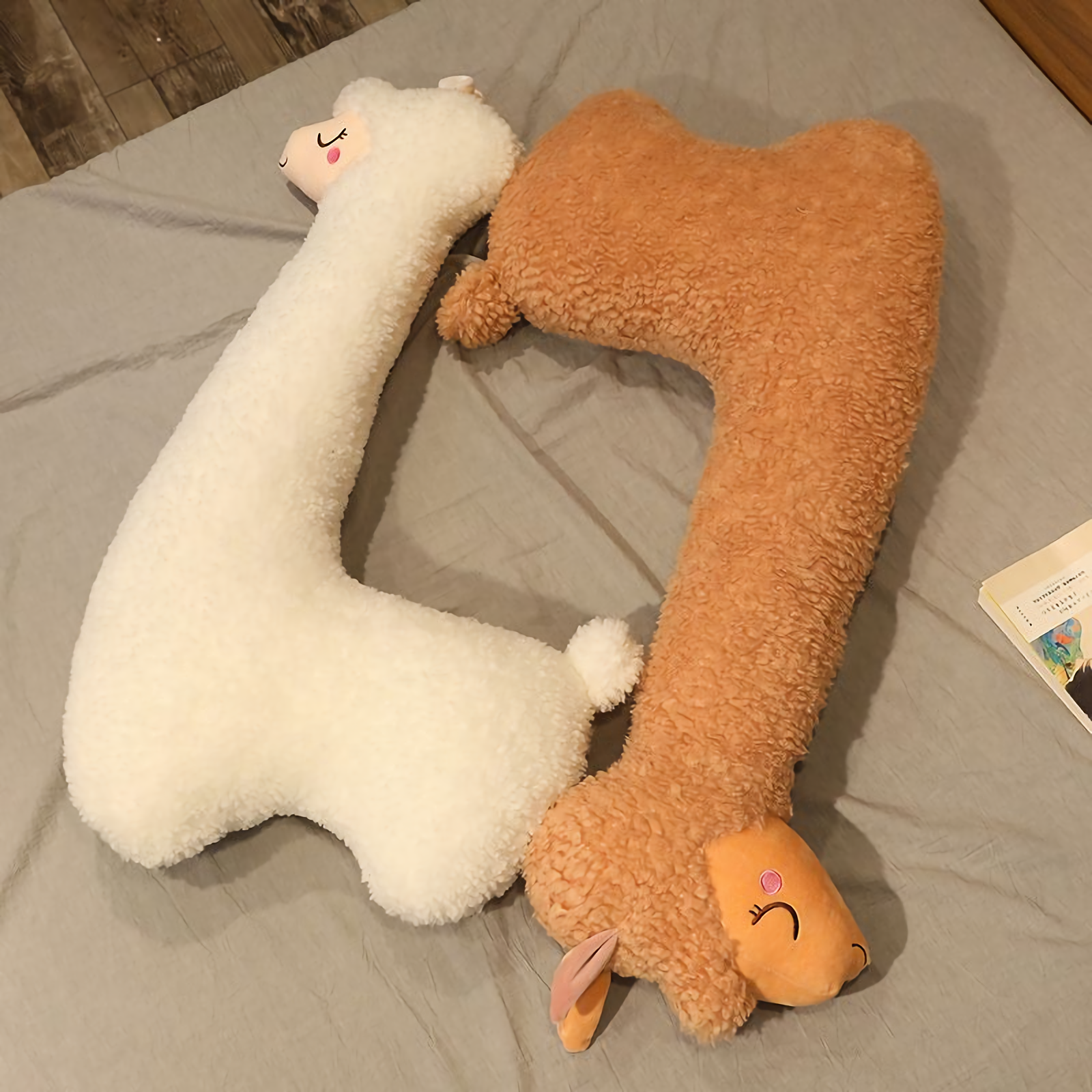 White and brown long alpaca plush pillows lying on a bed