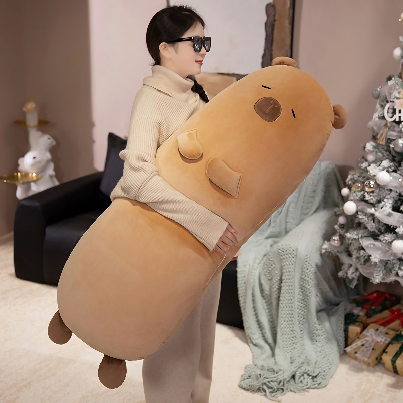 Woman with sunglasses hugging a tan capybara bolster pillow