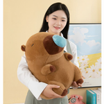 Woman holding a brown capybara plush with a blue nose bubble