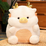 White pig-dragon plush cushion with golden horns on a wicker mat, showing its cream belly in a cozy indoor setting.
